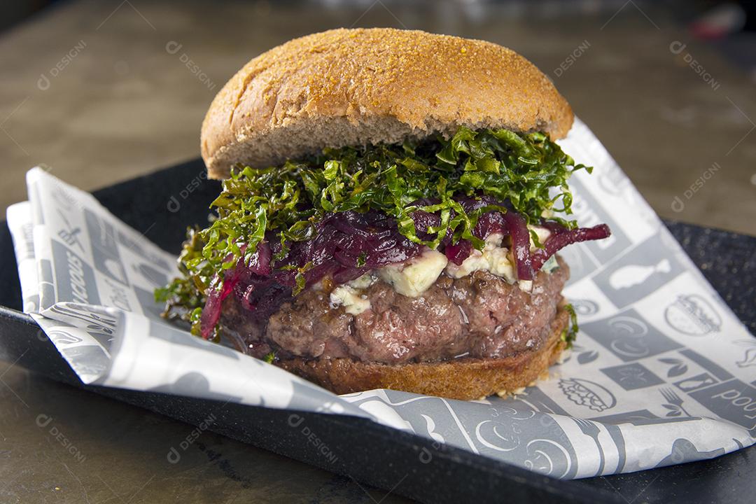 Hambúrguer de queijo com queijo azul, cebola e batatas fritas de repolho sobre fundo de pedra.