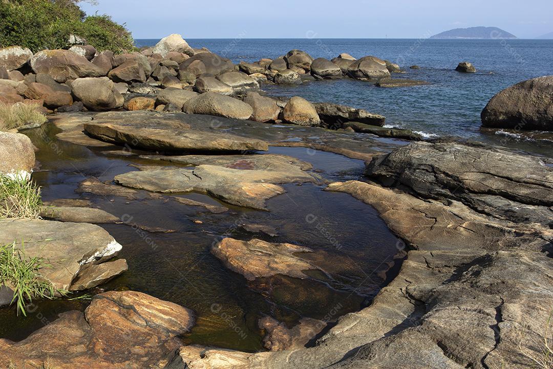 Rio que flui para o mar em uma praia na ilha de Ilhabela, Brasil.