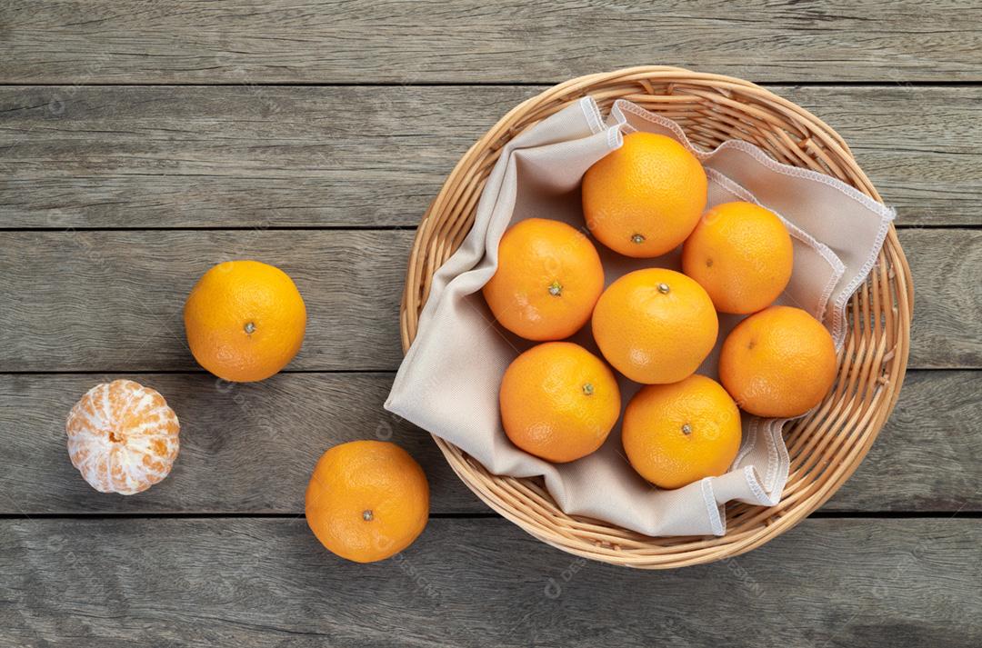 Tangerinas com frutas cortadas sobre a mesa de madeira