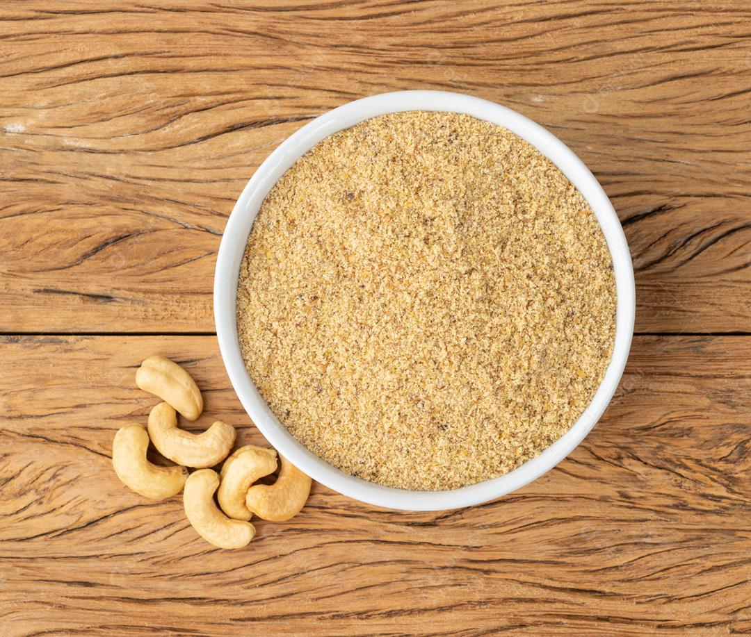 Farinha de castanha de caju em uma tigela sobre a mesa de madeira. Farinha sem glúten