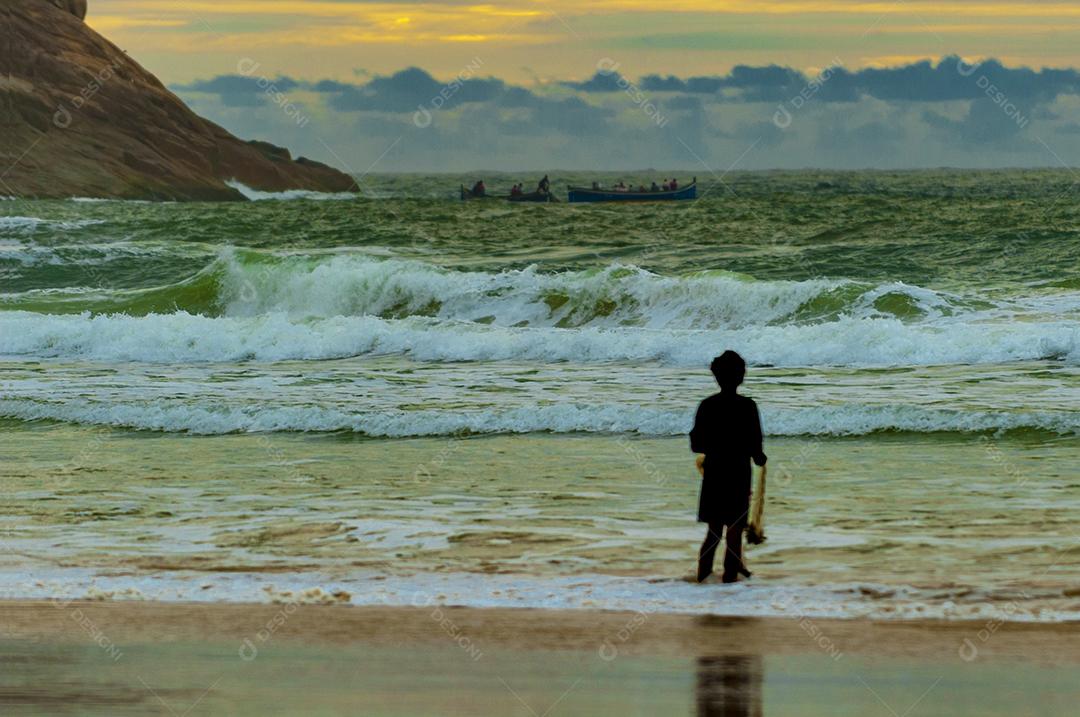 Menino olhando a paisagem praia céu nublado