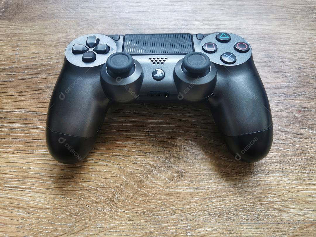 Controlador de jogos de videogame cinza PlayStation isolado na vista superior de fundo de madeira.