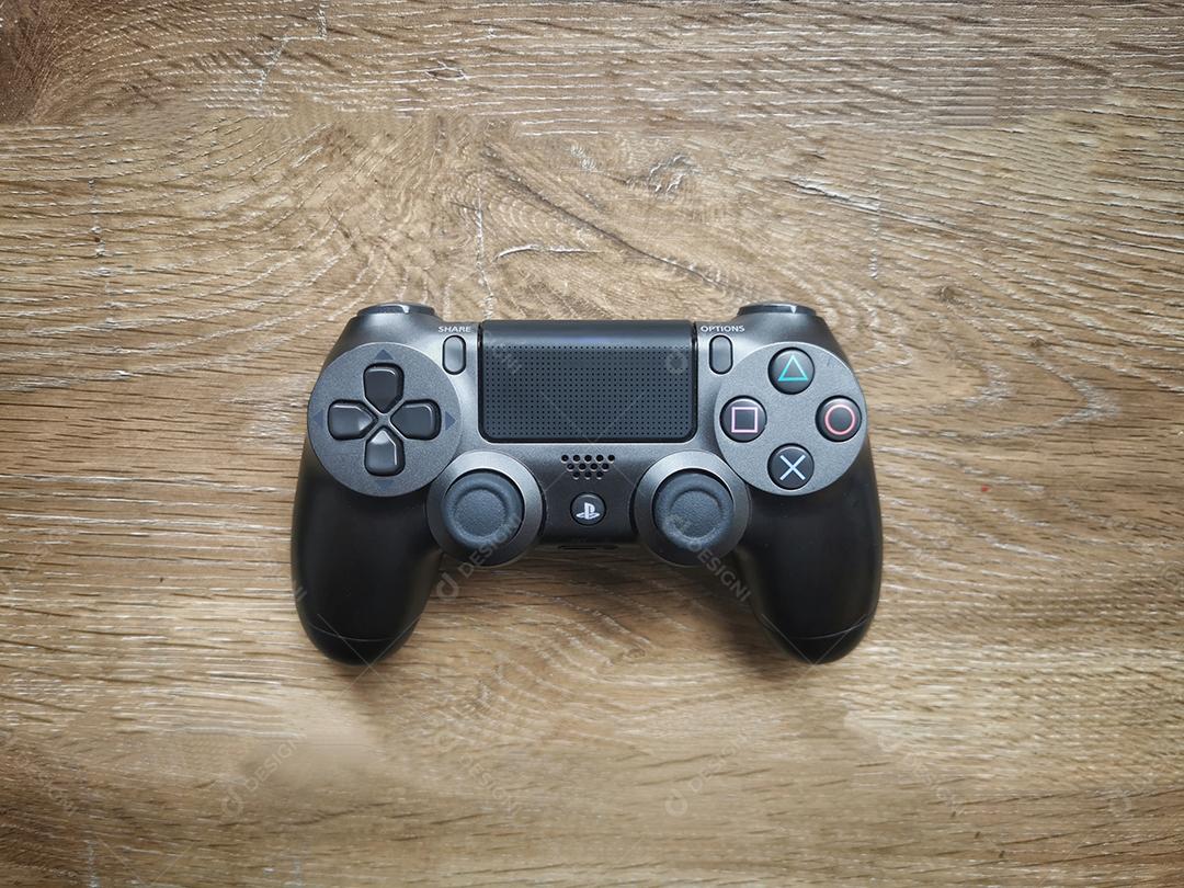 Controlador de jogos de videogame cinza PlayStation isolado na vista superior de fundo de madeira.
