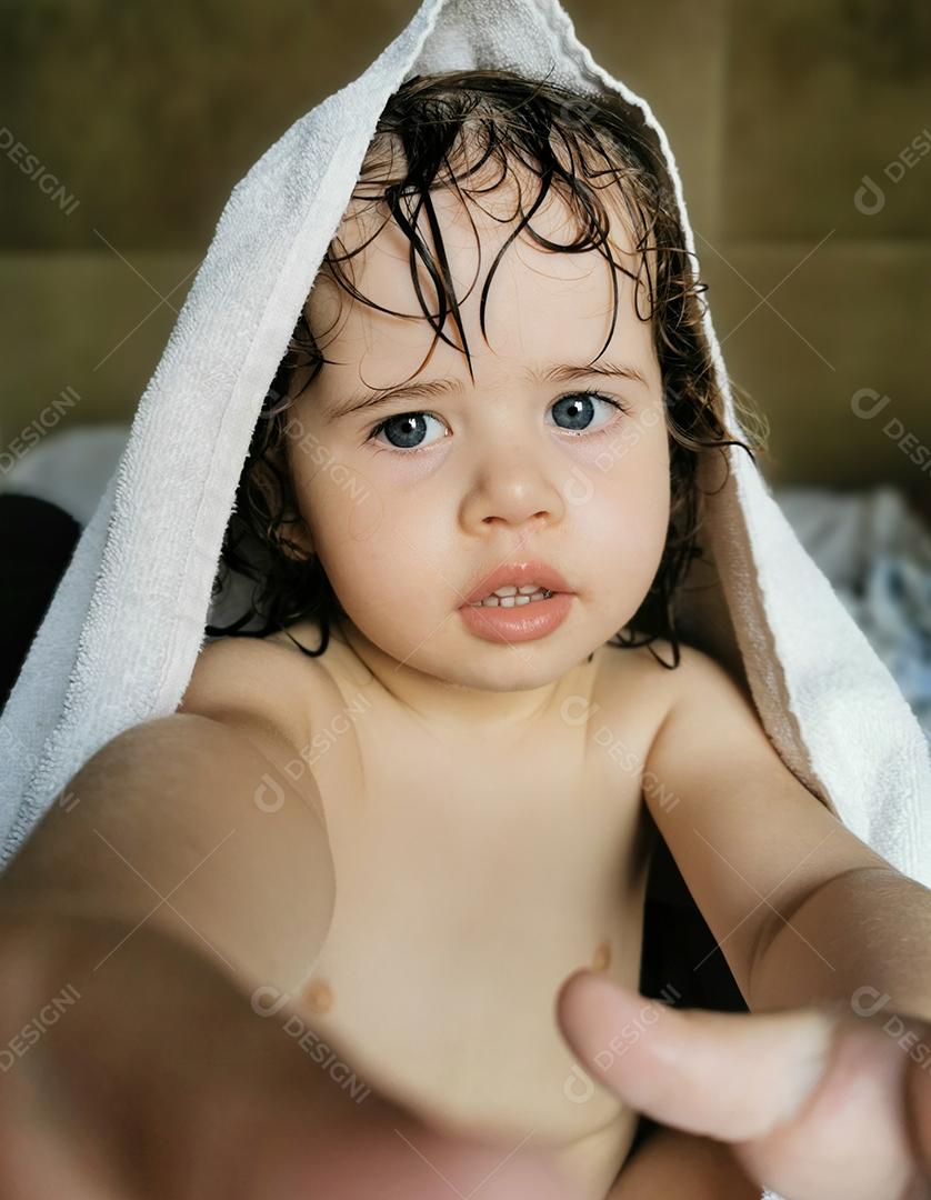 Menina brincando com a toalha na cabeça após o banho..