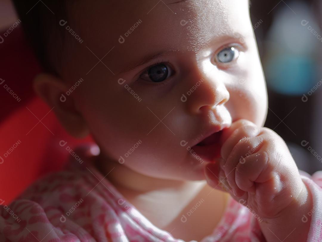 bebê de olhos azuis comendo um pedaço de pão.