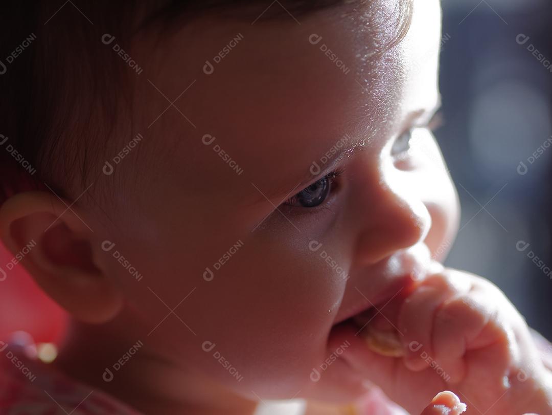 bebê de olhos azuis comendo um pedaço de pão.