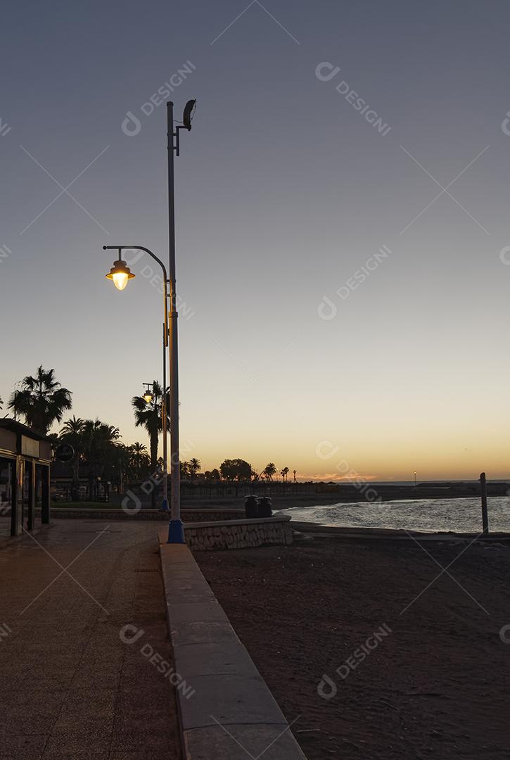 view of sea and light pole on Pedregalejo beach at dusk.
