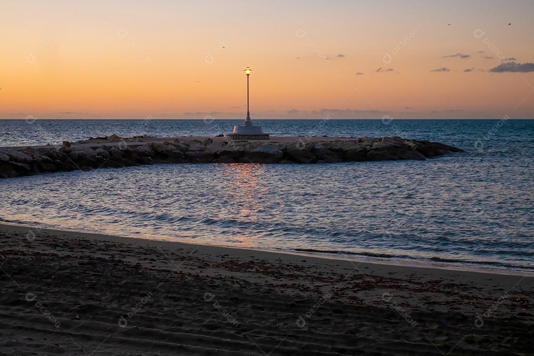 Vista de mar e poste de luz na praia de Pedregalejo ao entardecer.