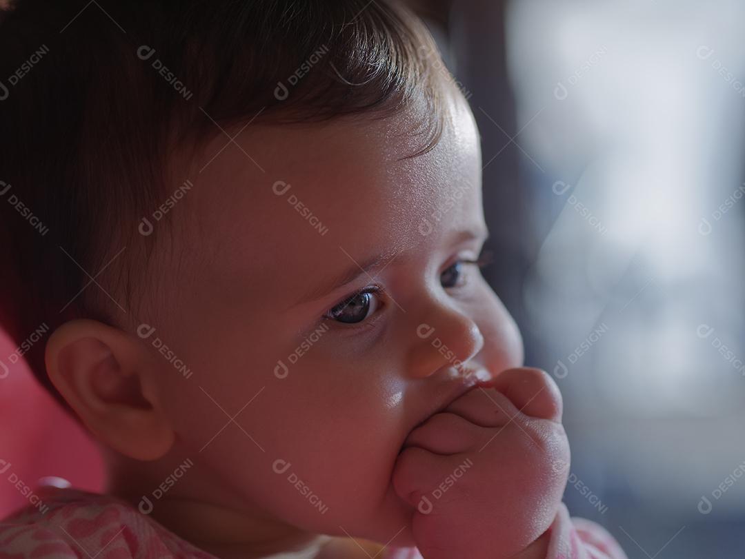 bebê com olhos azuis, olhando para o lado.