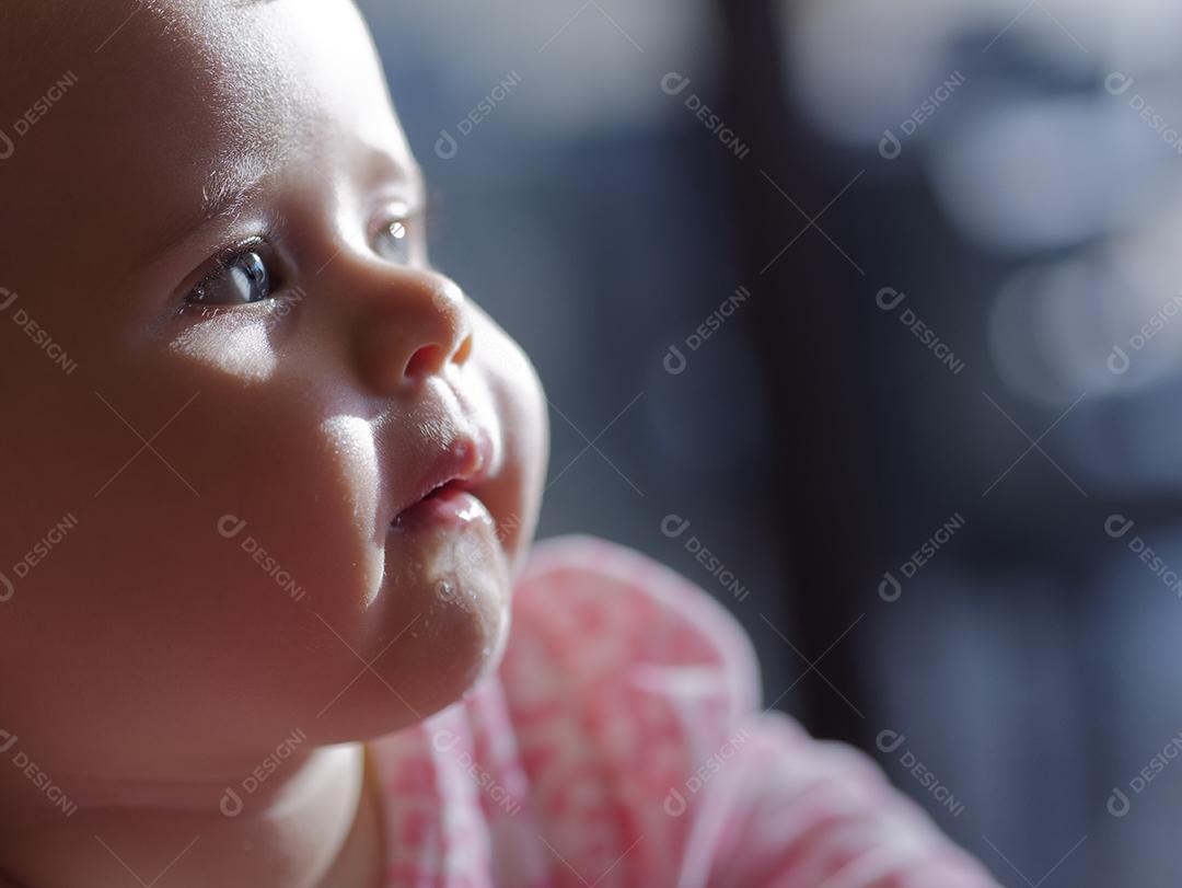 bebê com olhos azuis, olhando para o lado.