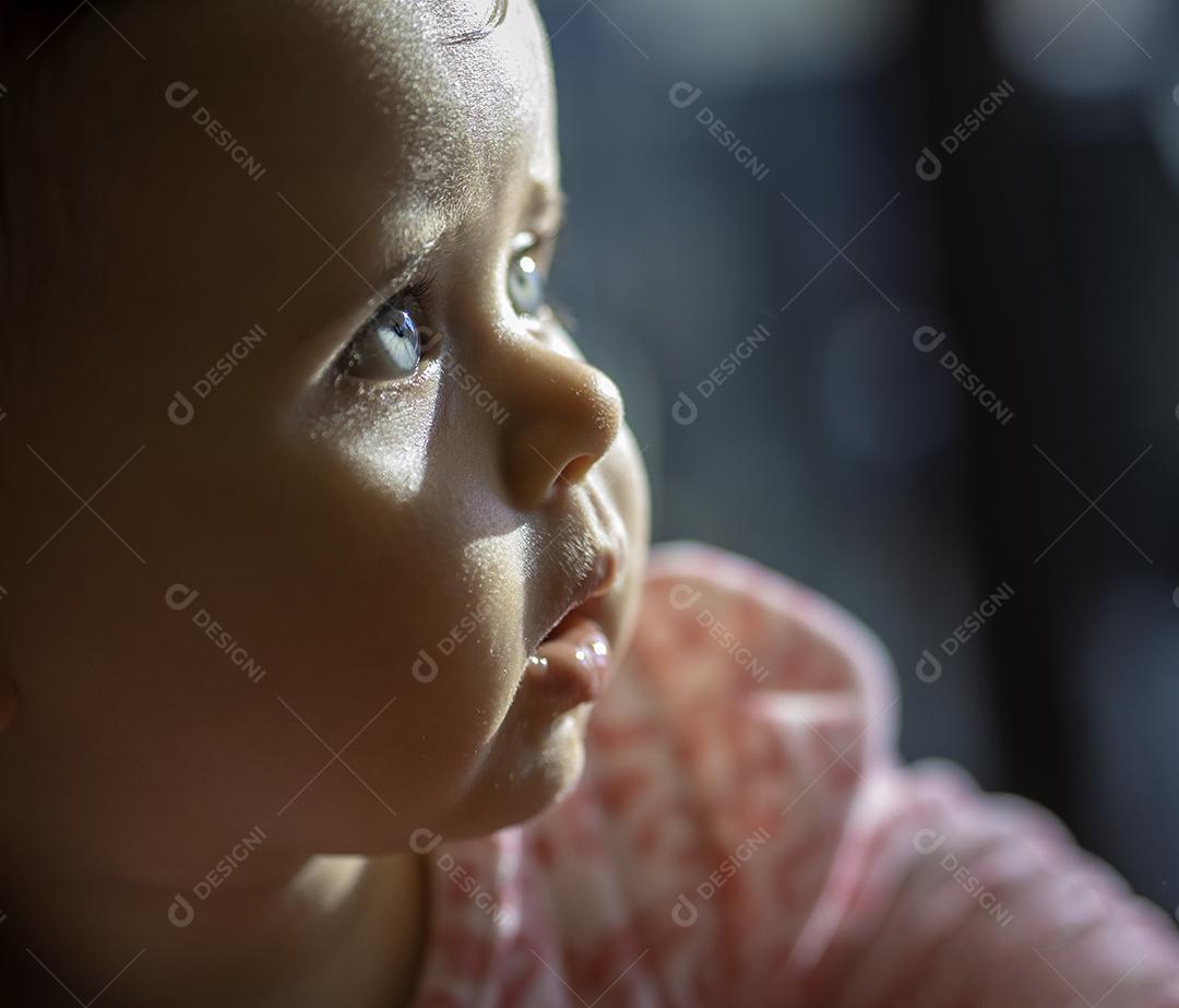 bebê com olhos azuis, olhando para o lado.