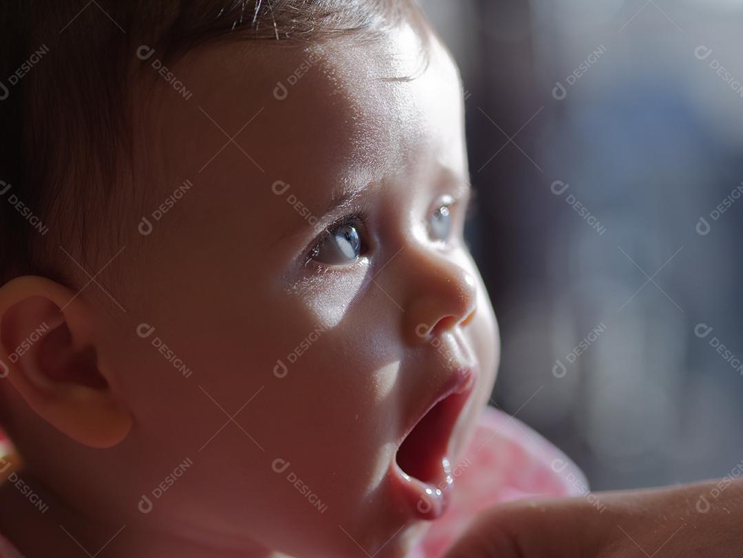 bebê com olhos azuis, olhando para o lado.