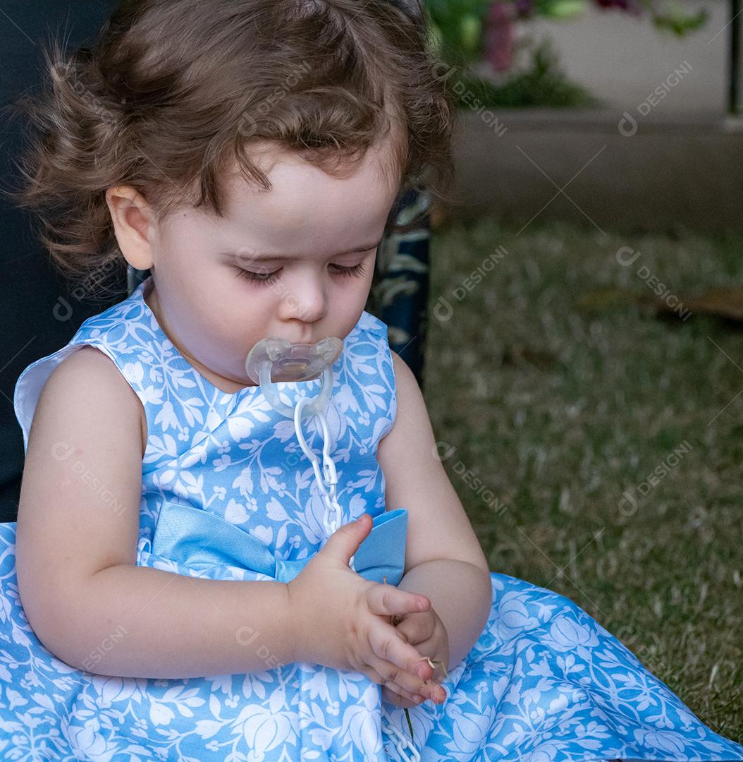 Retrato de uma menina brincando com grama.
