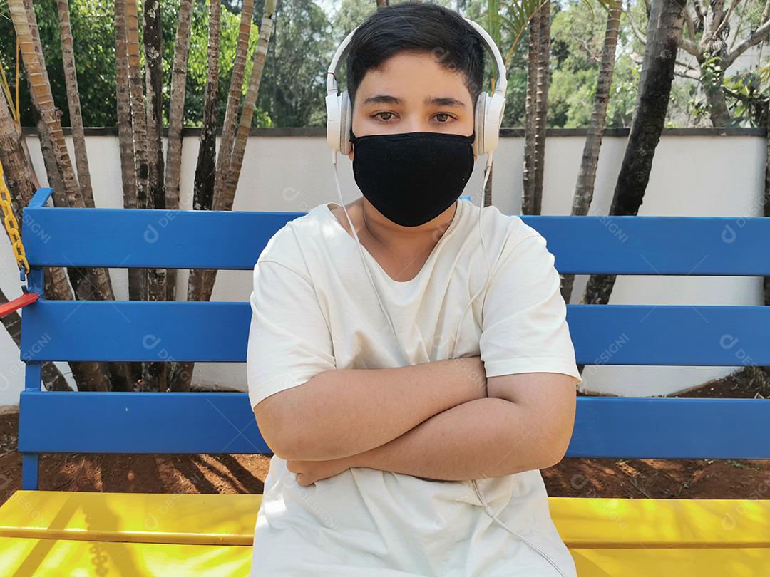 Menino brasileiro usando máscara e fones de ouvido posando para a câmera