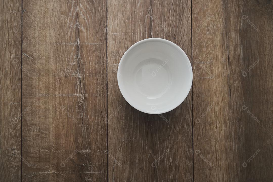 top view of an empty white bowl on a wooden background