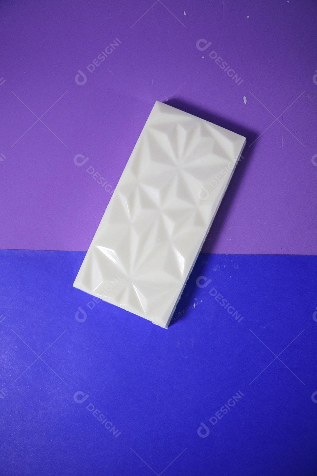 Barra de chocolate branco sobre fundo azul e roxo