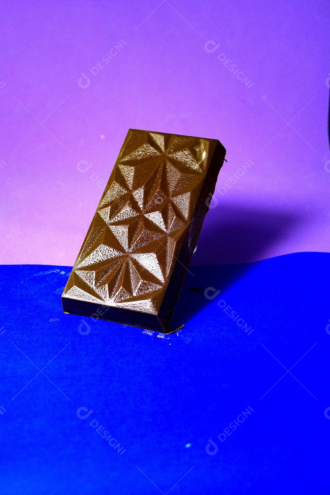 Barra de chocolate sobre fundo azul e roxo