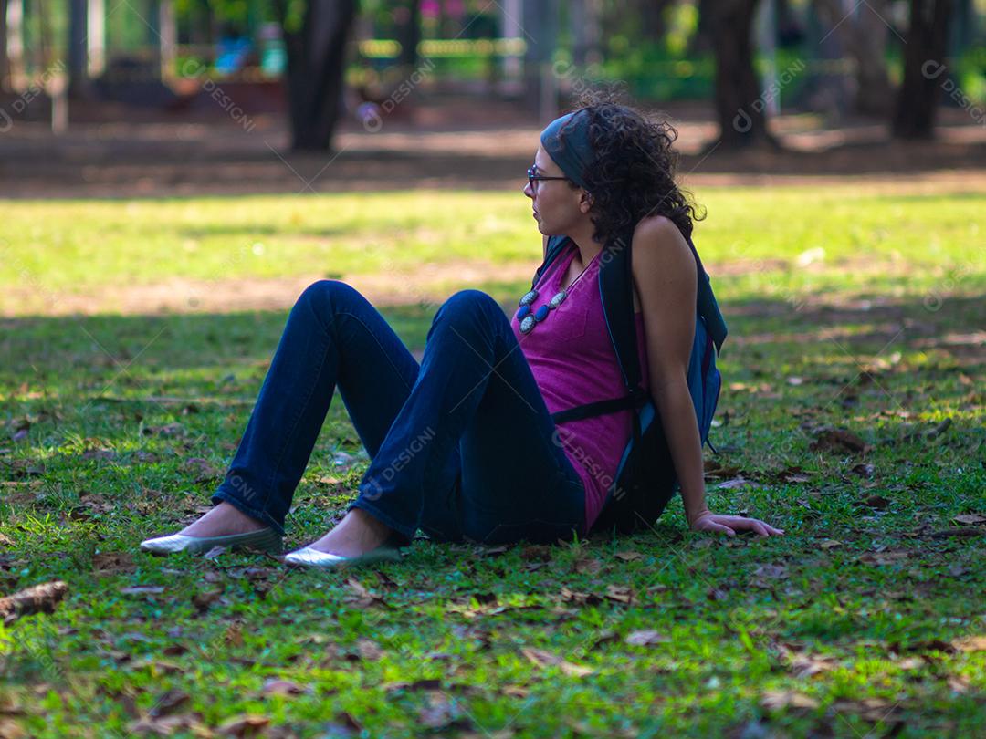 Mulher jovem hippie relaxante na grama no parque.