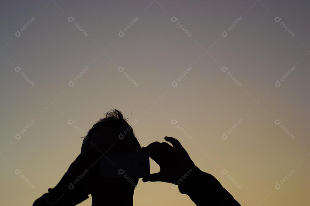 Silhueta de um homem tirando foto com celular.