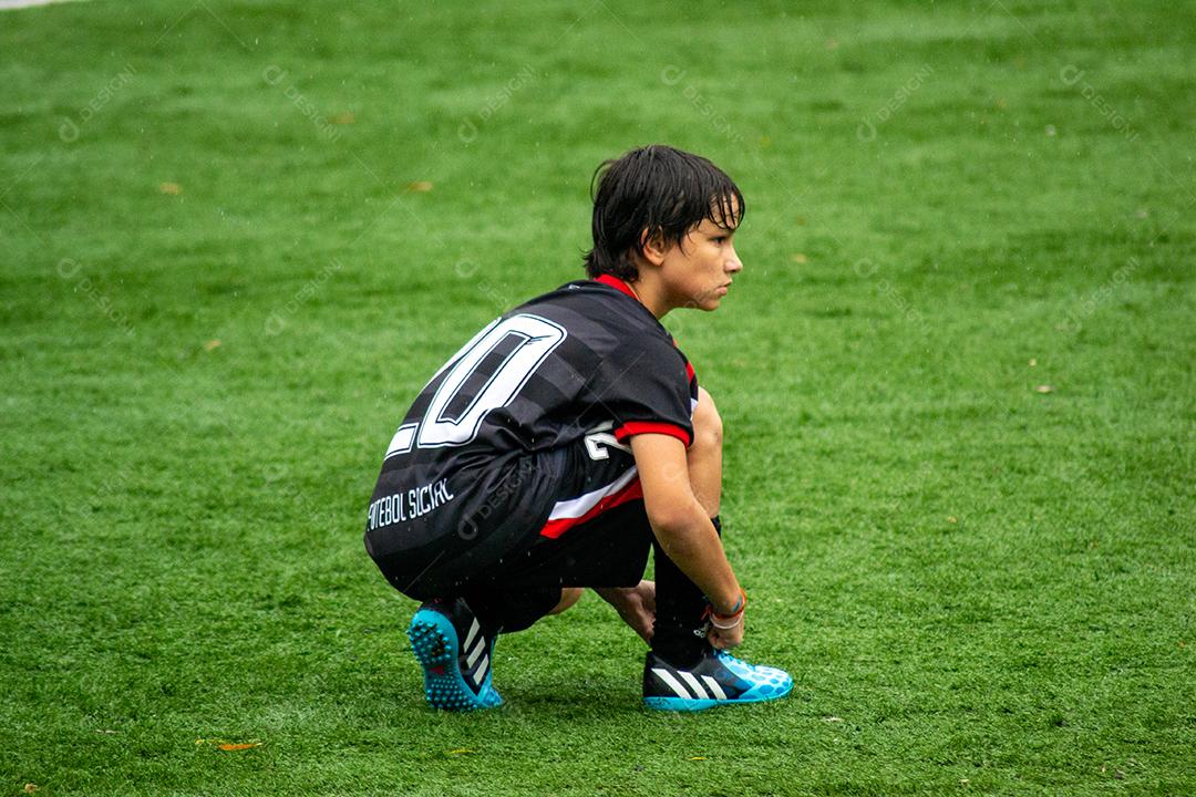 Young Boy correndo no campo de futebol durante a chuva