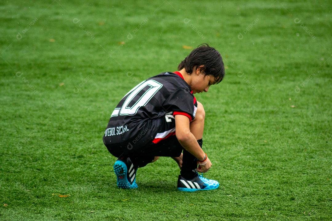 Young Boy correndo no campo de futebol durante a chuva