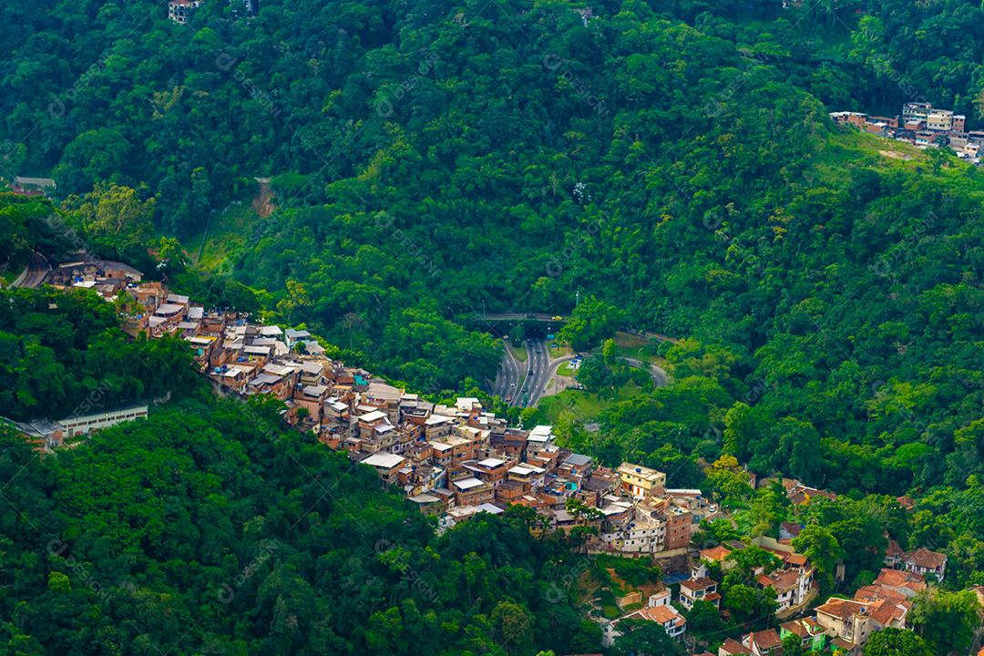 Vista aérea de favelas no Rio de Janeiro cercadas por floresta tropical.
