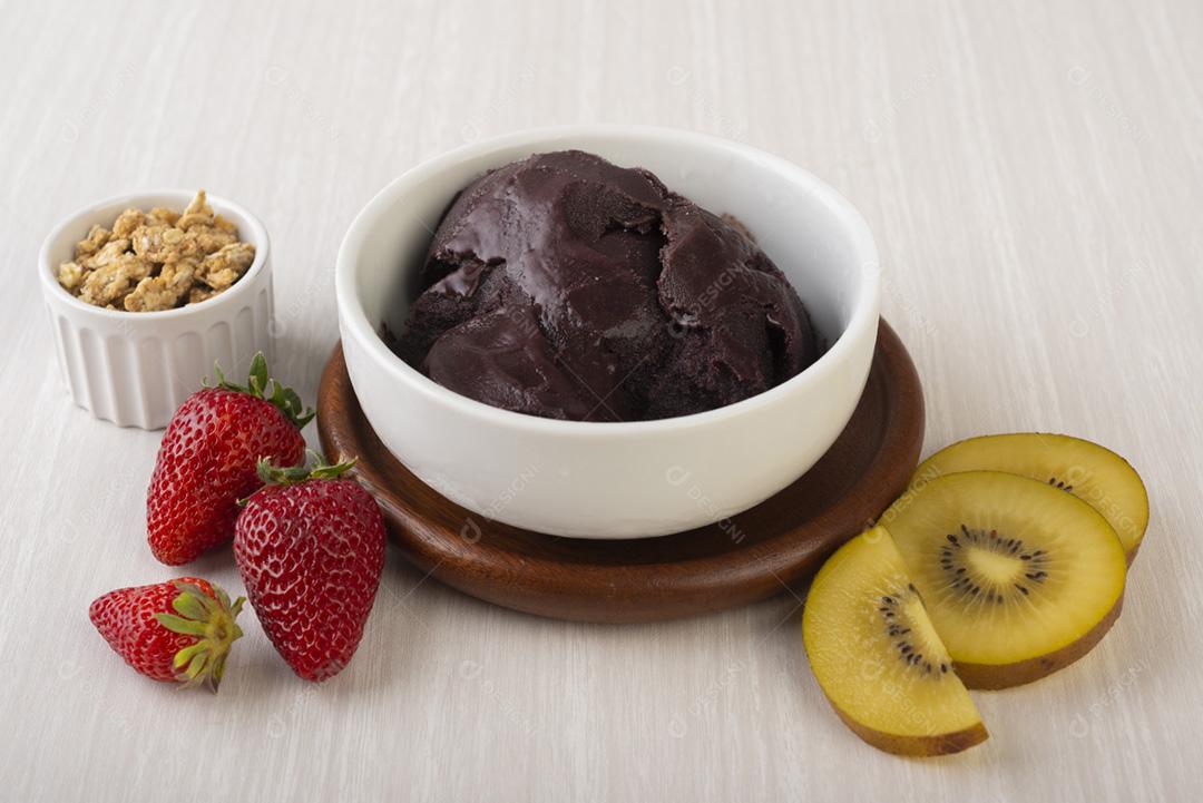 Tigela de açaí típica brasileira com frutas e muesli sobre b de madeira