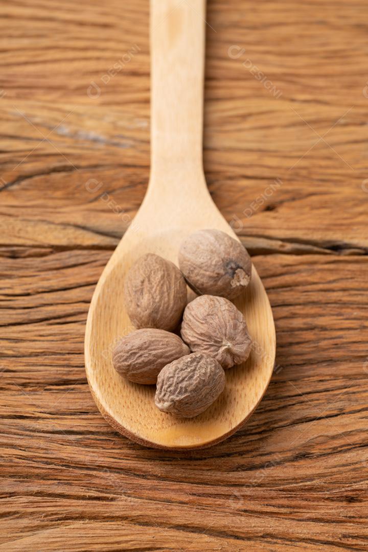 Closeup de noz-moscada em uma colher sobre a mesa de madeira