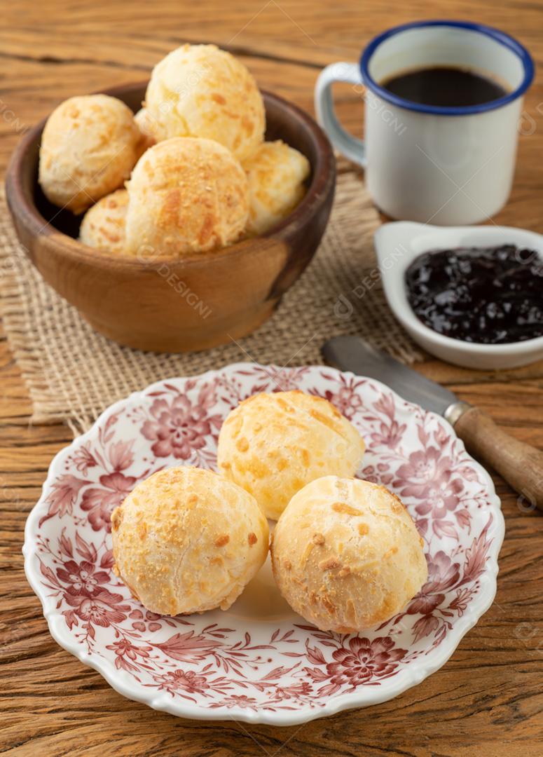 Pão de queijo brasileiro típico em uma cesta, café e geléia