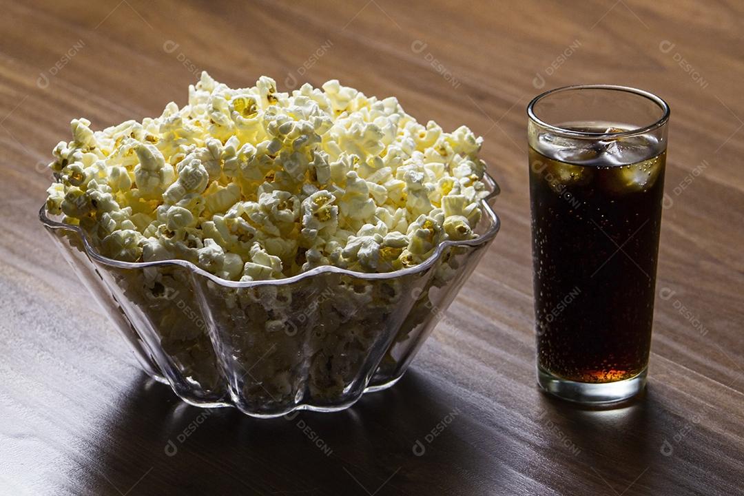 Pipoca e refrigerante na mesa de madeira