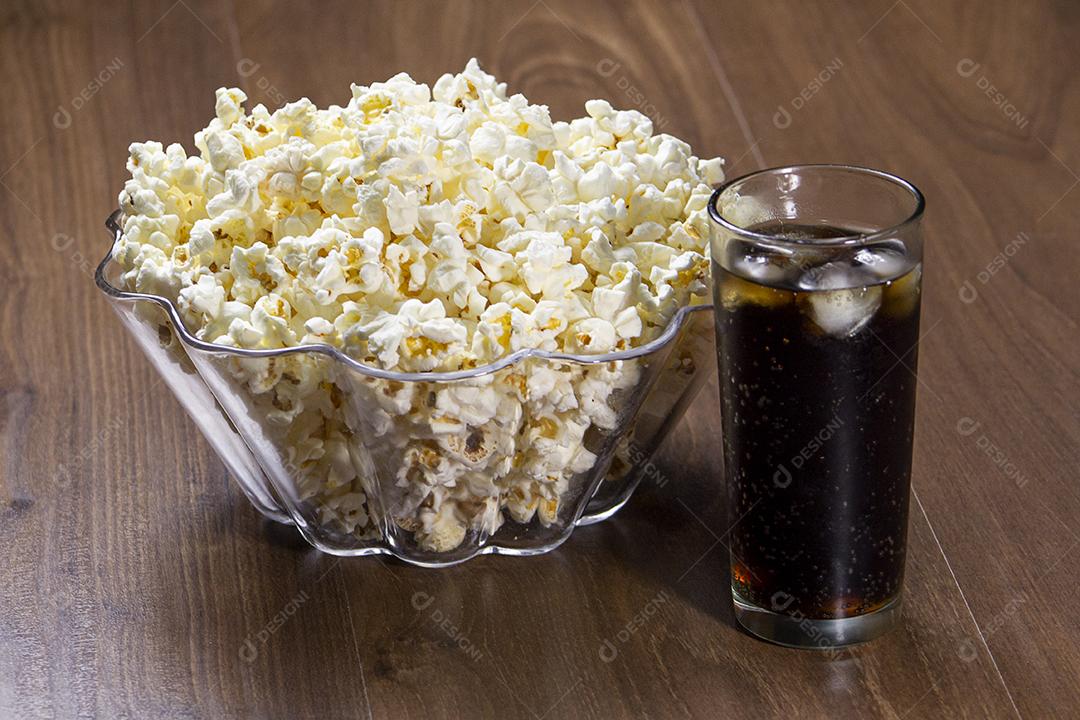 Pipoca e refrigerante na mesa de madeira