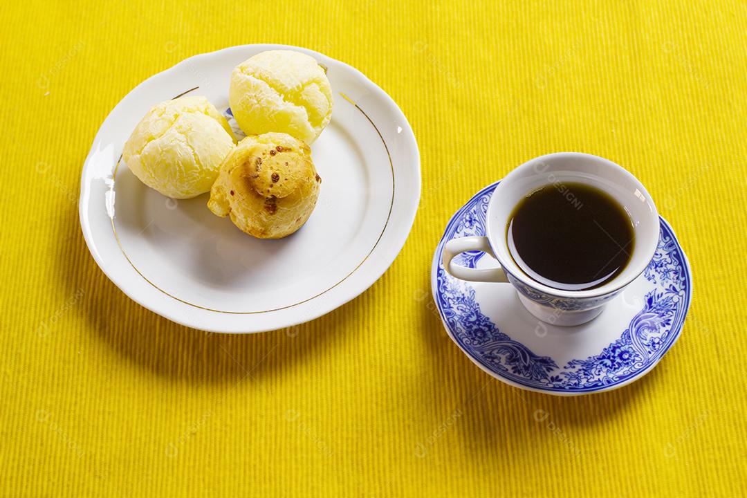 Xícara de café de porcelana chinesa e pão de queijo em cima de jogo americano amarelo