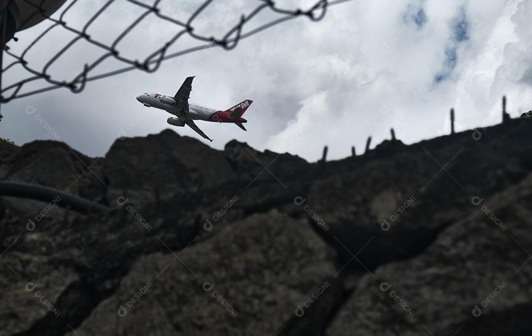 Avião passando entre grau e parede.