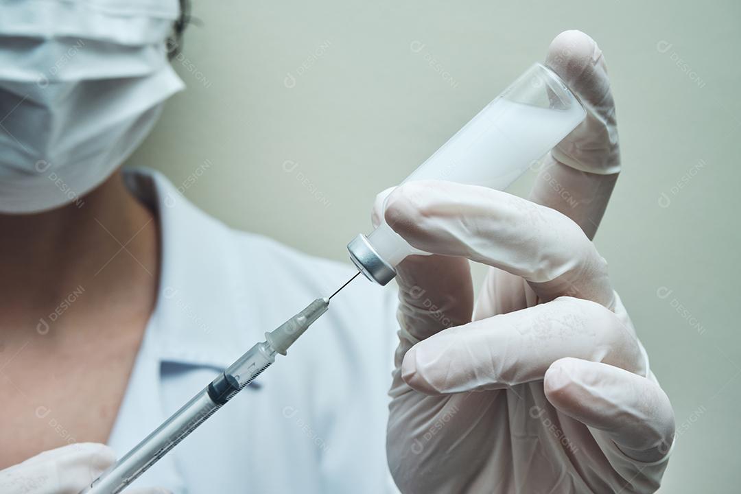 Vista de uma enfermeira preparando a dose da vacina.