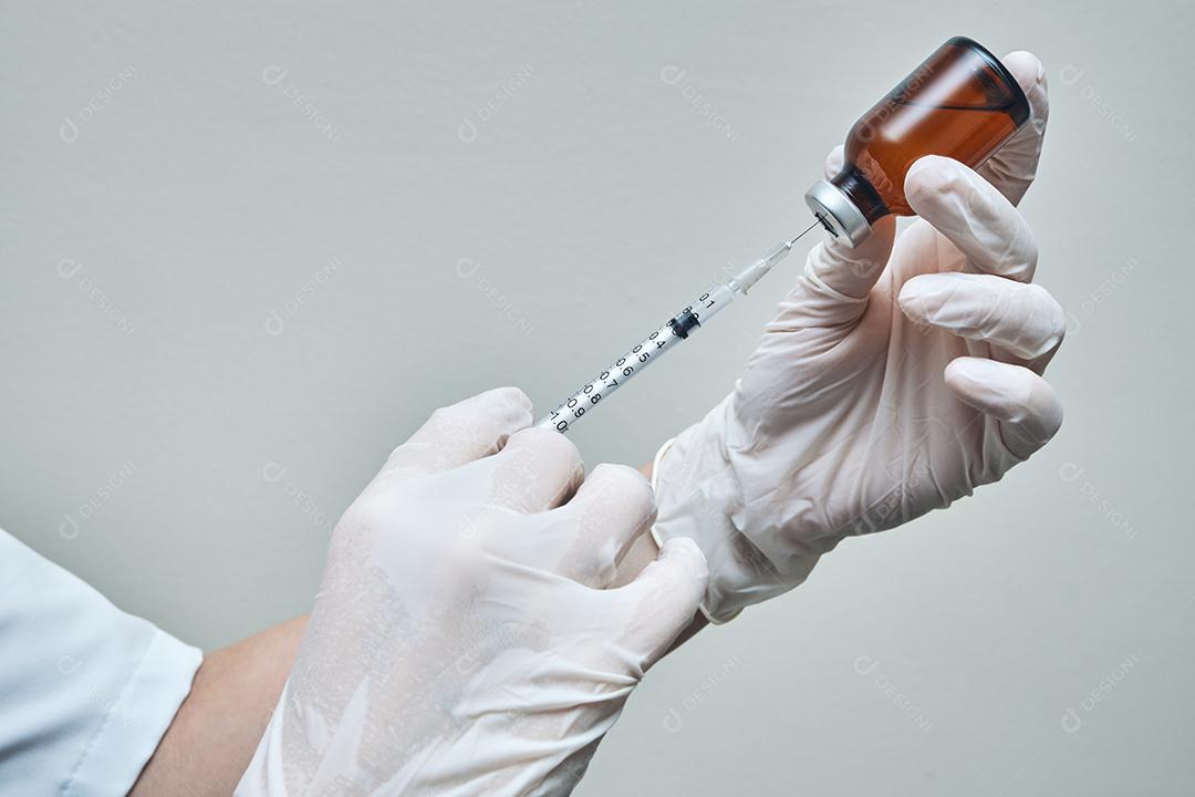 Feche as mãos da enfermeira preparando a dose da vacina com espaço de cópia.