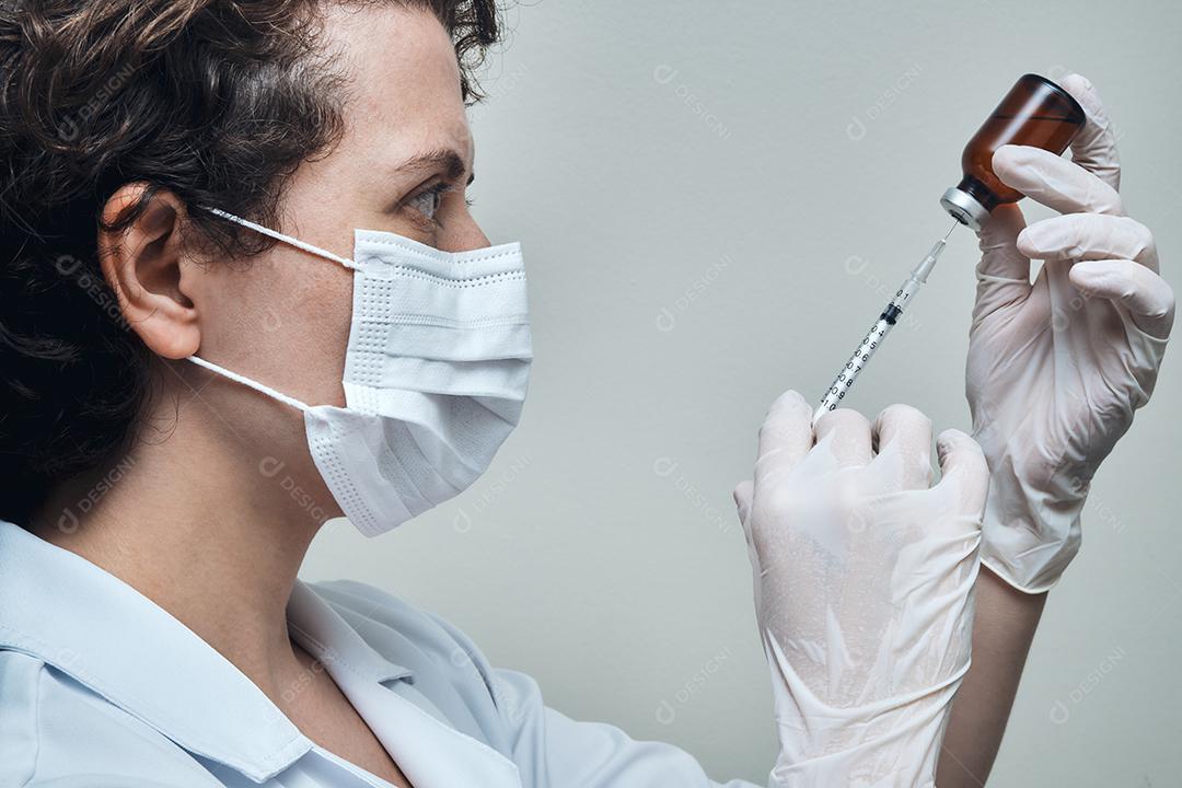 Vista de uma enfermeira preparando a dose da vacina.