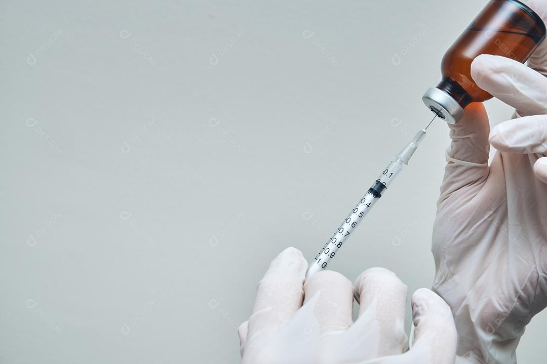 Feche as mãos da enfermeira preparando a dose da vacina