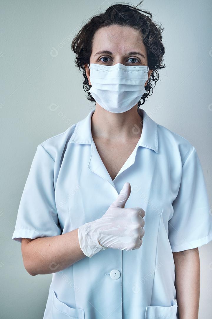 enfermeira usando máscara e luvas rezando com as palmas das mãos fechadas