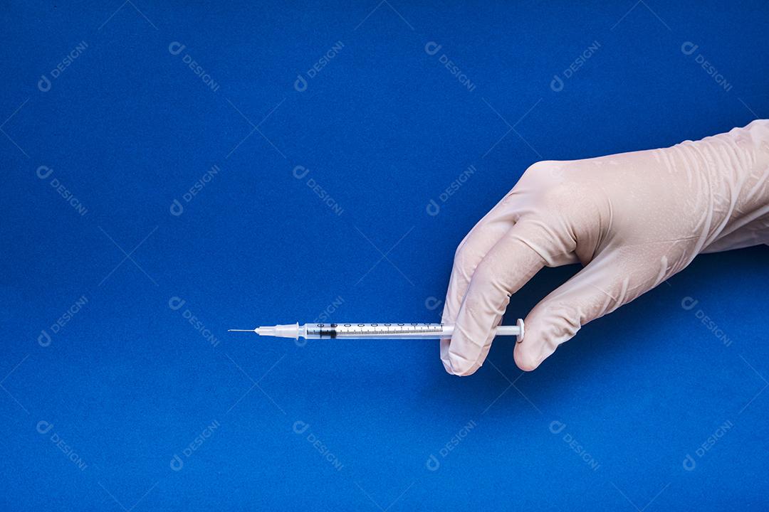 Imagem de uma enfermeira preparando a dose da vacina em fundo azul