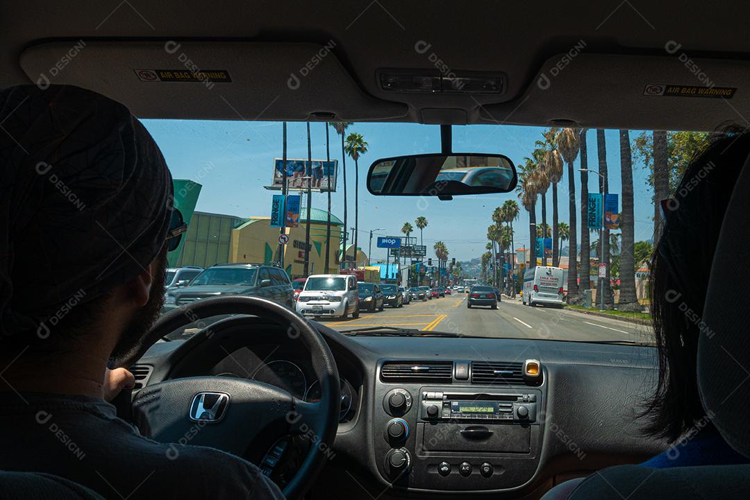 Vista de dentro do carro com casal passeando pelas ruas de los angeles.