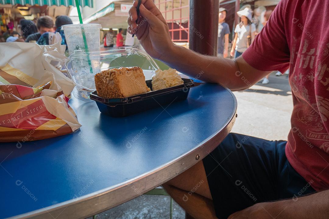 Homem tendo uma fatia de cheesecakes no mercado de Los Angles.