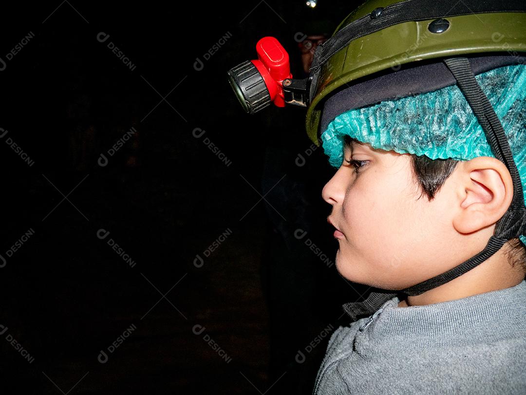Menino dentro da caverna usando capacete