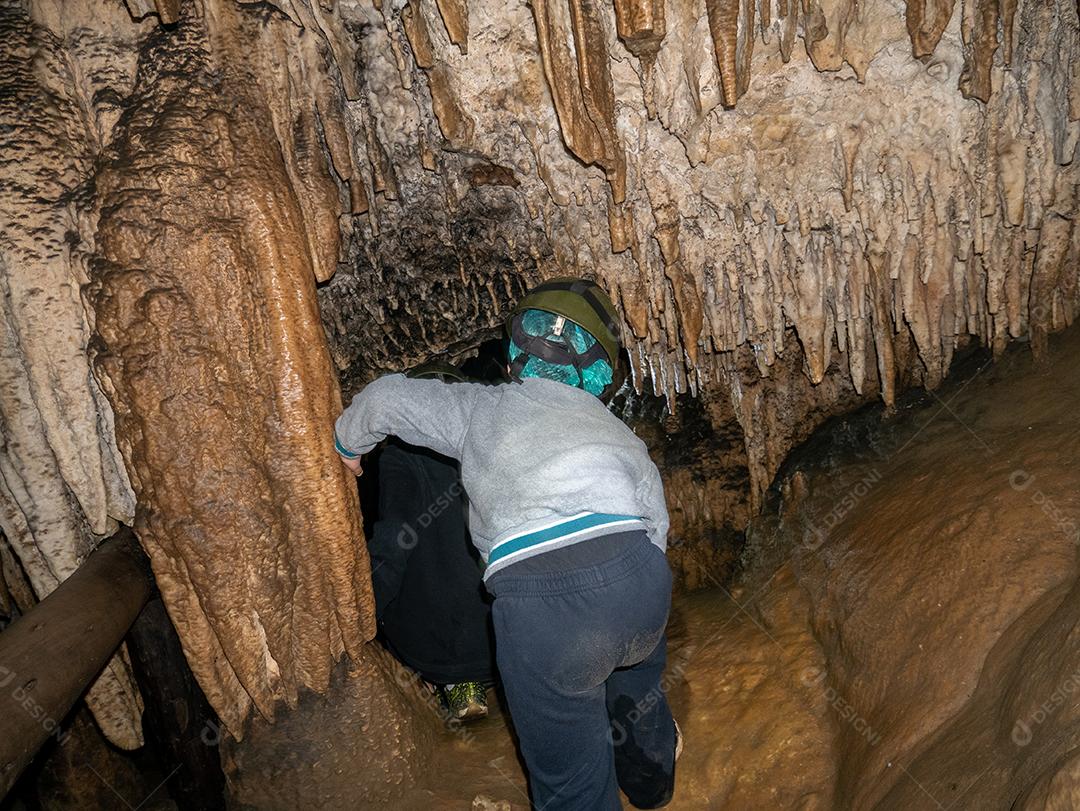 Garotinho entrando e explorando caverna no Brasil.