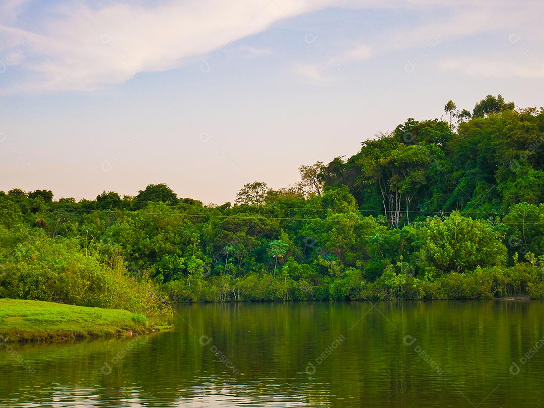 vista do pôr do sol com árvores e céu refletindo no lago.