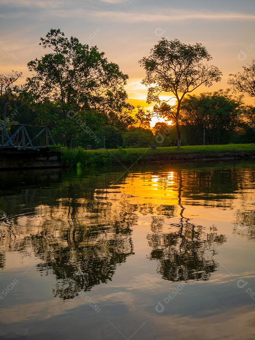 vista do pôr do sol com árvores e céu refletindo no lago.