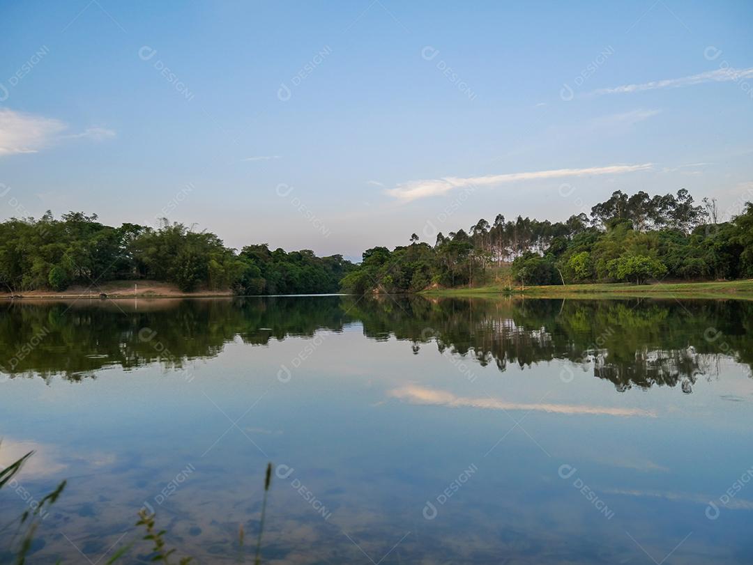 vista do pôr do sol com árvores e céu refletindo no lago.