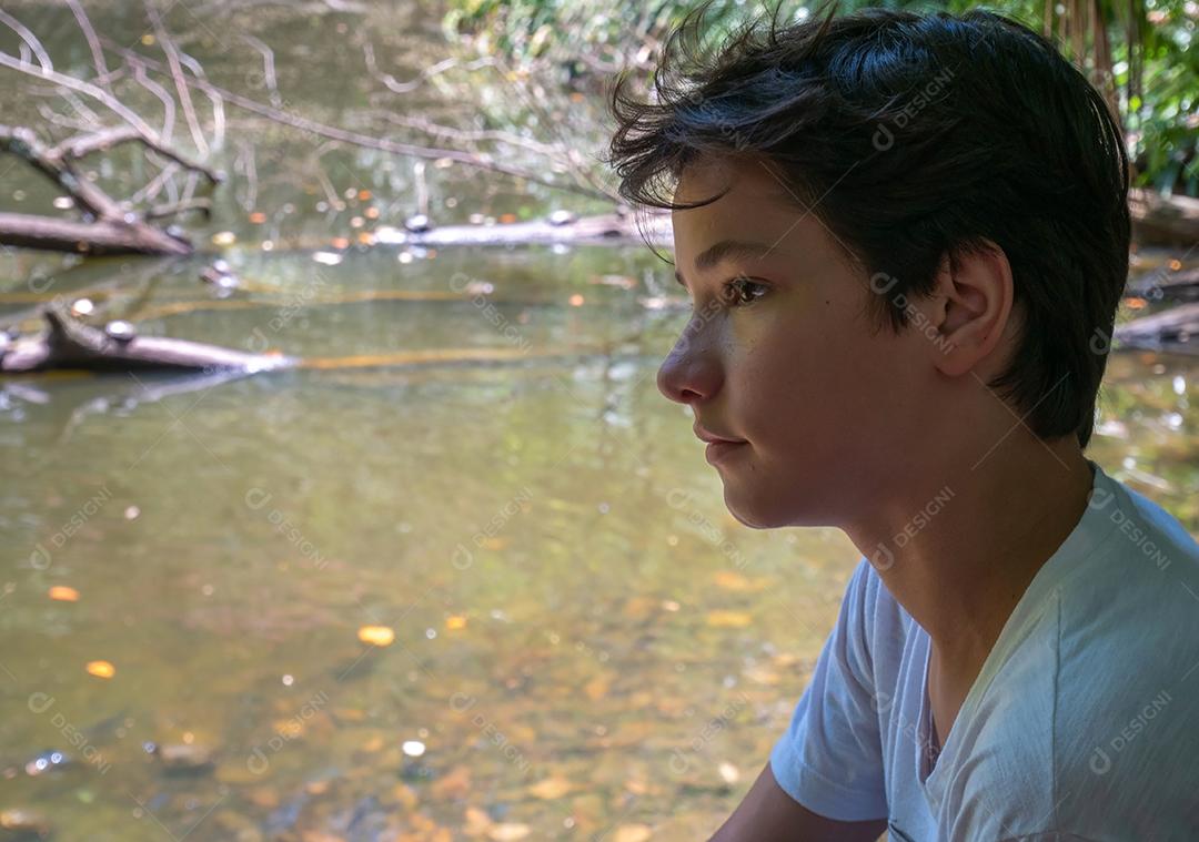 Retrato de menino brasileiro com fundo de natureza.