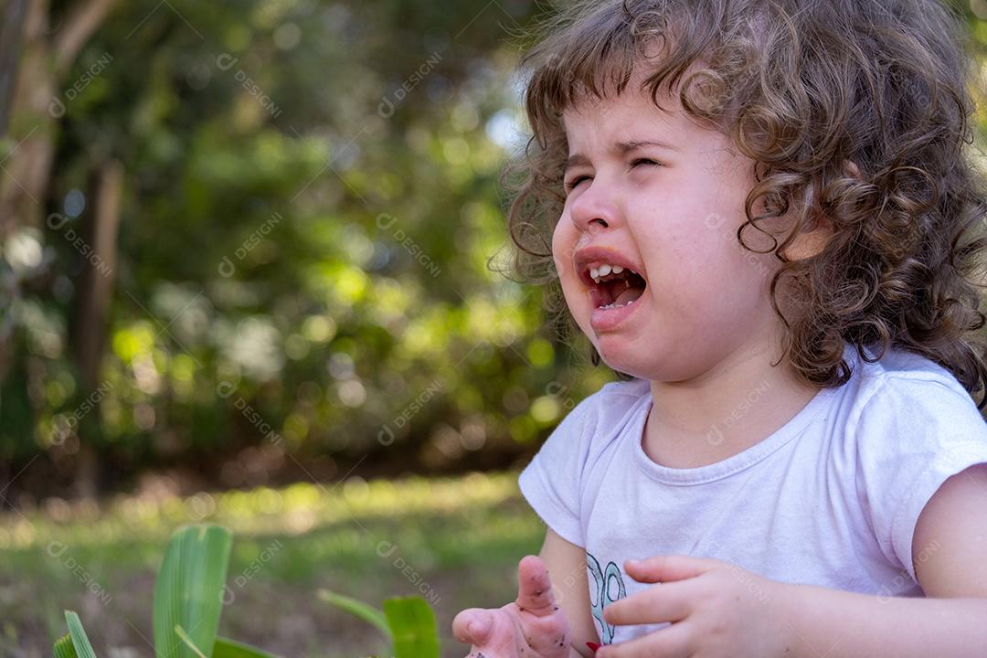 Vista de uma linda garotinha triste e chorando na fazenda.