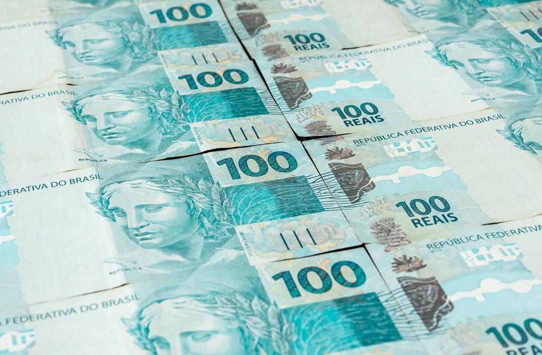 Um groud de notas de cem reais espalhadas