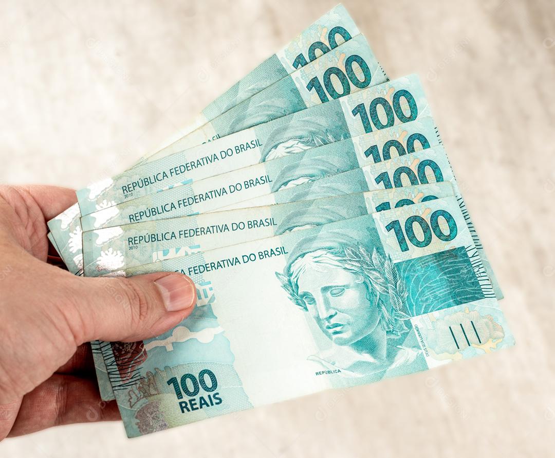 Um groud de notas de cem reais espalhadas